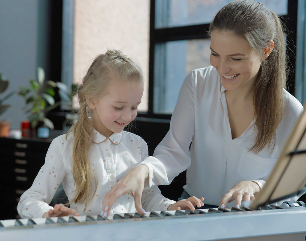 Smiling piano teacher guiding young student at Fort Myers piano lesson